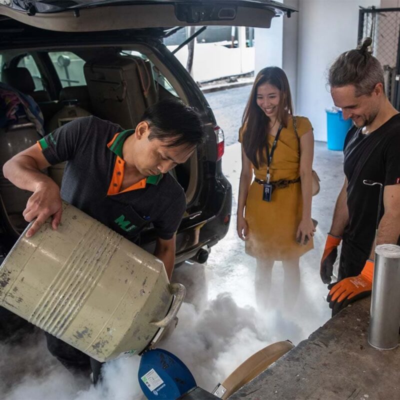 A group of three scientists at a mobile lab pouring liquid nitrogen onto samples