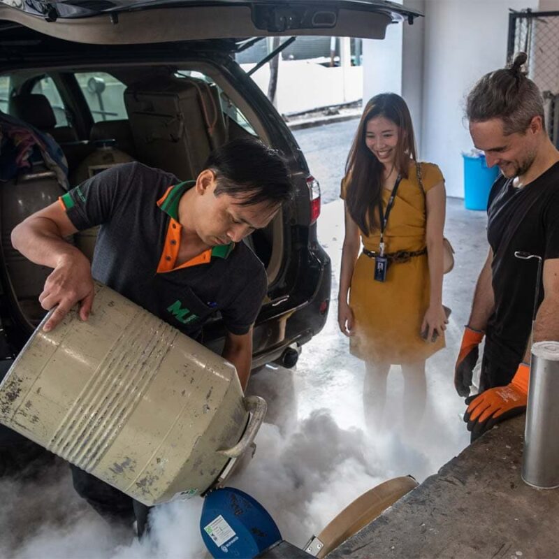 A group of three scientists at a mobile lab pouring liquid nitrogen onto samples